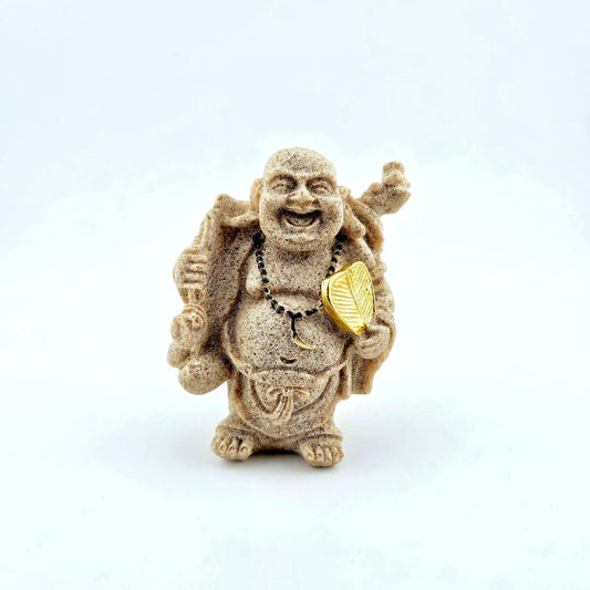 Statue of a laughing Buddha holding a gold leaf on a white background