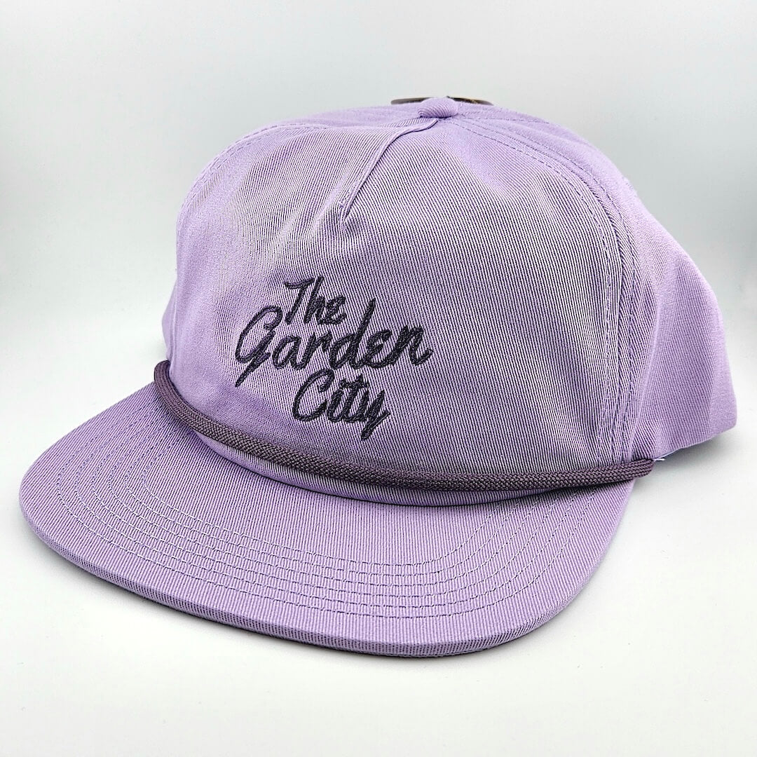 Purple cap with 'The Garden City' text on a light gray background