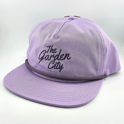 Purple cap with 'The Garden City' text on a light gray background