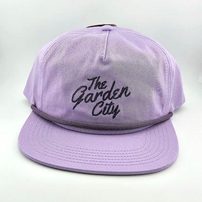 Purple cap with 'The Garden City' text on a light gray background