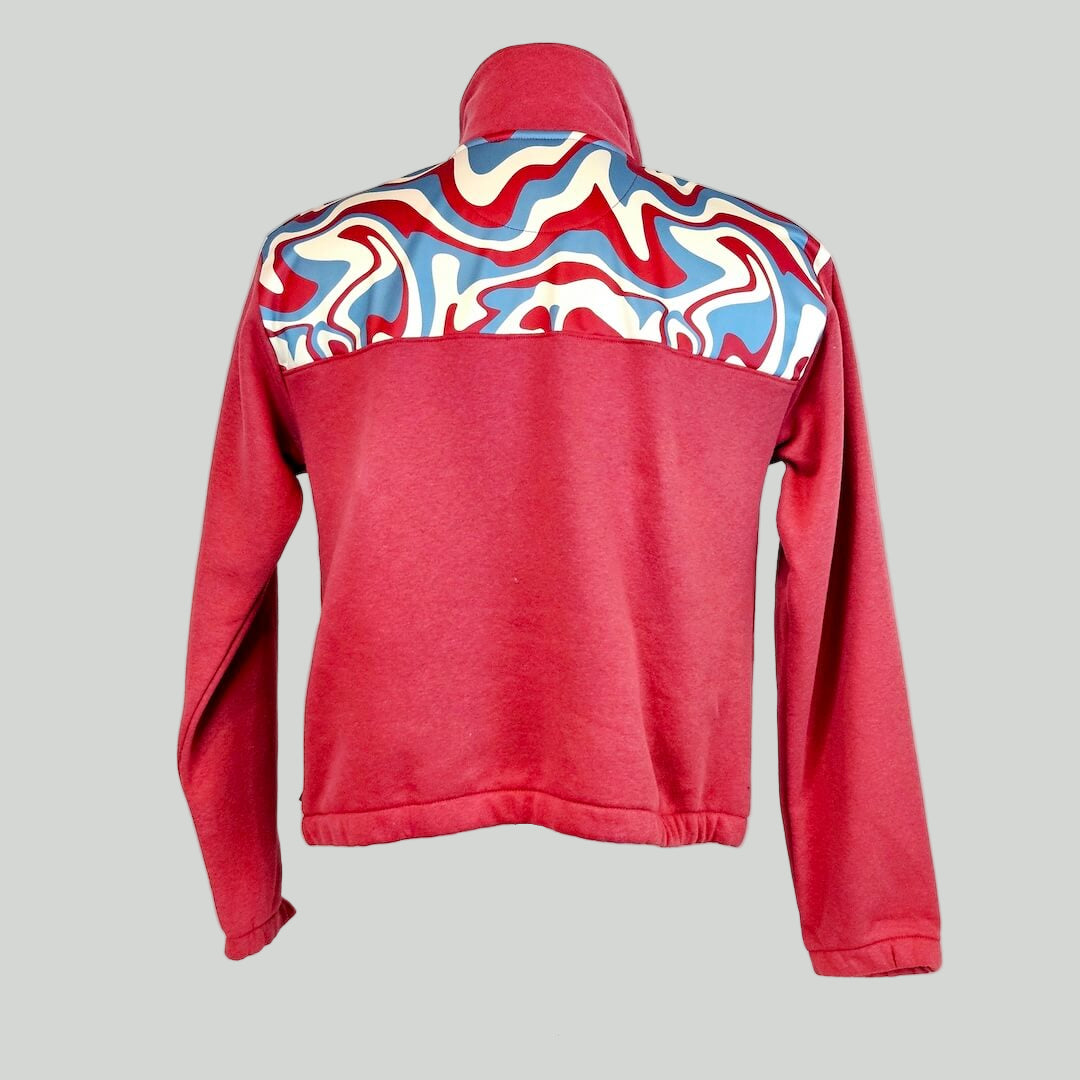 Red jacket with colorful pattern on the back across shoulders displayed on a mannequin against a white background