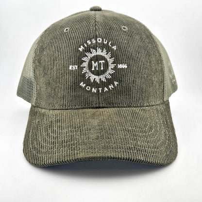 Green corduroy had with circular sunburst in center with "MISSOULA, MONTANA" encircling it with "MT" in center of sun.