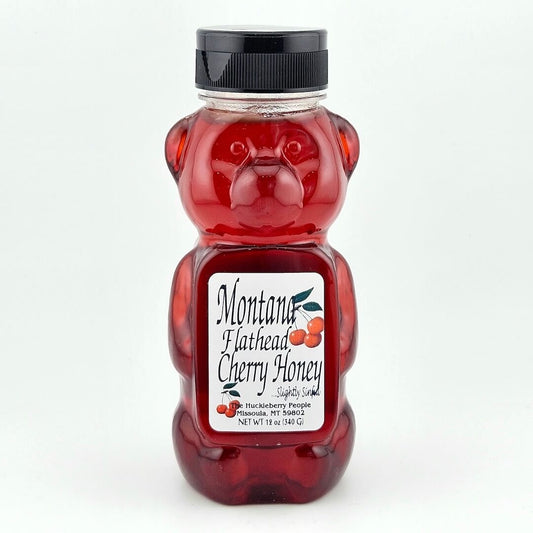 Bear shaped jar of Flathead Cherry honey against white background. 
