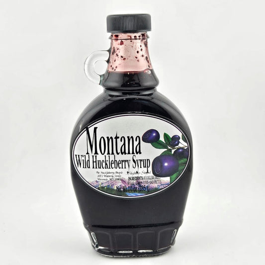 Glass bottle with small handle & black lid. Label has enlarged image of huckleberries next to product info in black print.