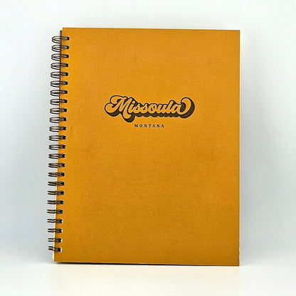Mustard yellow, spiral-bound notebook against white background.