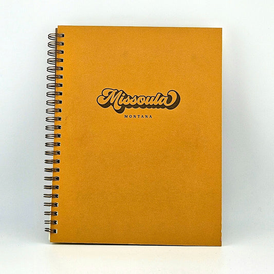 Mustard yellow, spiral-bound notebook against white background.