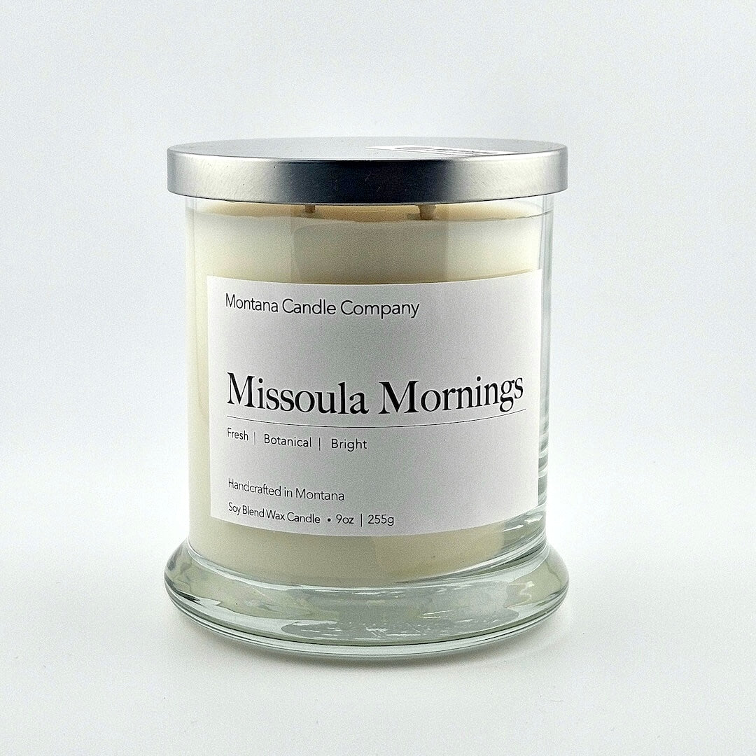 Glass jarred candle with silver lid, label with printed company name top, scent name in center, then listed scent components.