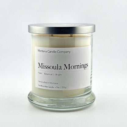 Glass jarred candle with silver lid, label with printed company name top, scent name in center, then listed scent components.