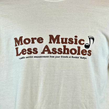 beige t-shirt with brown text 'More Music Less Assholes' and a black music note graphic on a beige background.