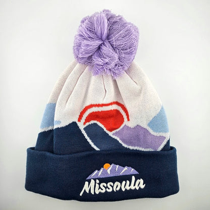 Beanie with purple pom-pom, colorful design, and 'Missoula' branding on a white background
