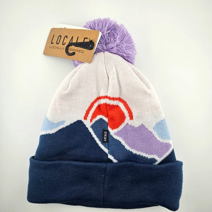 Knitted beanie with mountain design and purple pom-pom on a white background