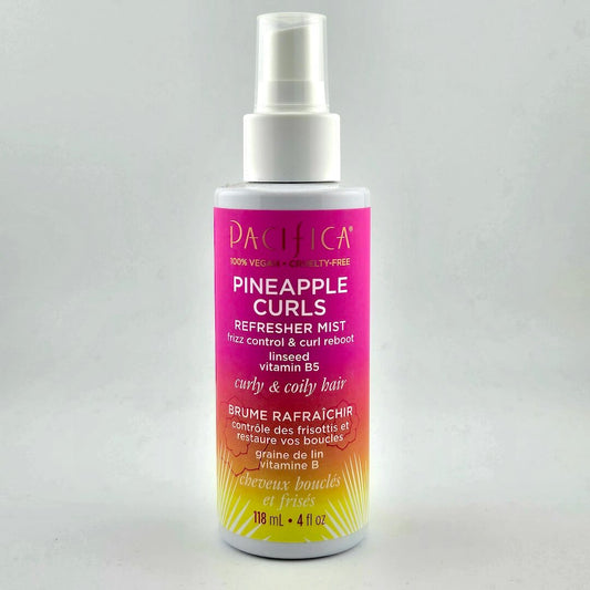 Pink/orange ombre spray bottle with white text with product information against white background.