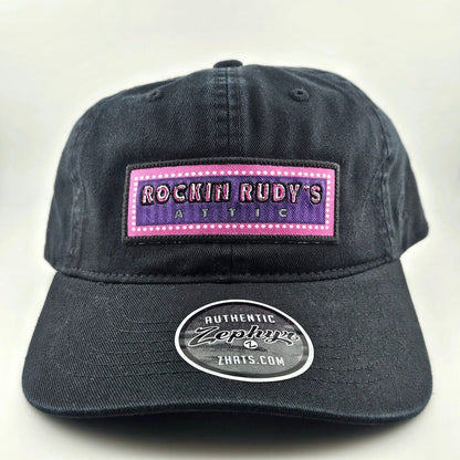 Black cap with 'Rockin Rudy's Attic' patch on a white background