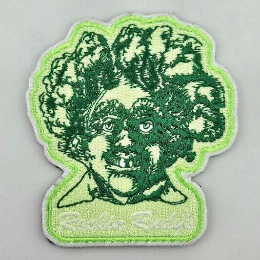 Embroidered patch with a green creature design on a gray background