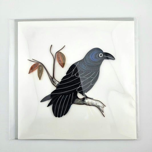 Quilled artwork of a crow on a branch with leaves on a white background