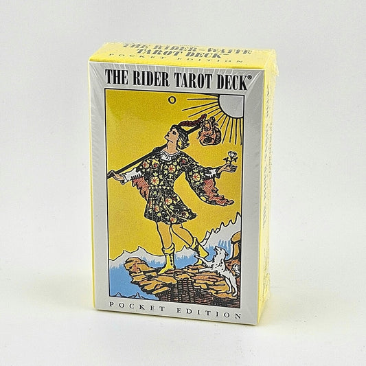 White & yellow box of tarot cards with image of man in printed tunic walking off cliff beneath sun with dog at feet.