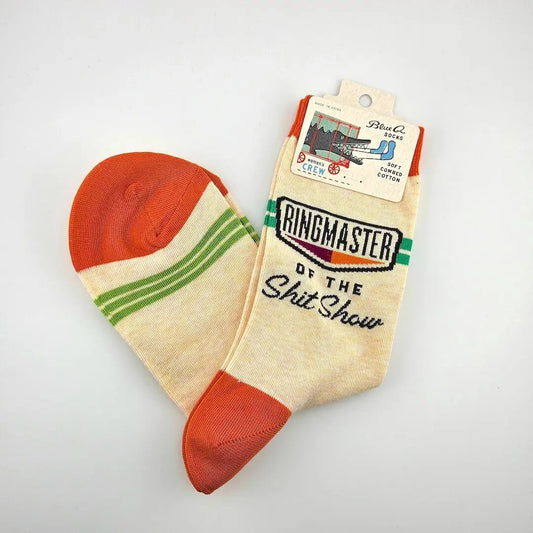 Beige sock with red toes and green stripes, featuring 'Ringmaster of the Shit Show' text, on a light gray background.