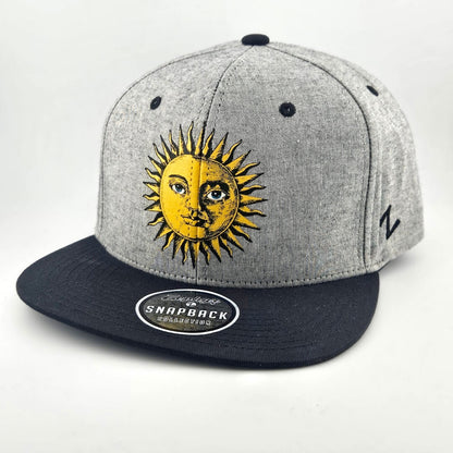 Grey heathered hat with black bill and stitching, yellow stylized sun in center of face. Sticker on bill.