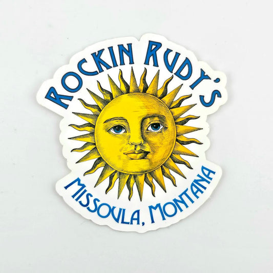 Sticker with sun design and text 'Rockin Rudt's Missoula, Montana' on a light gray background