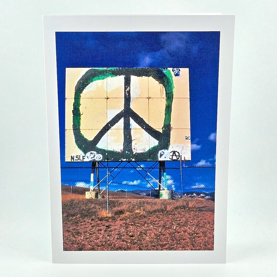 Peace symbol on a billboard with a blue sky and mountains in the background