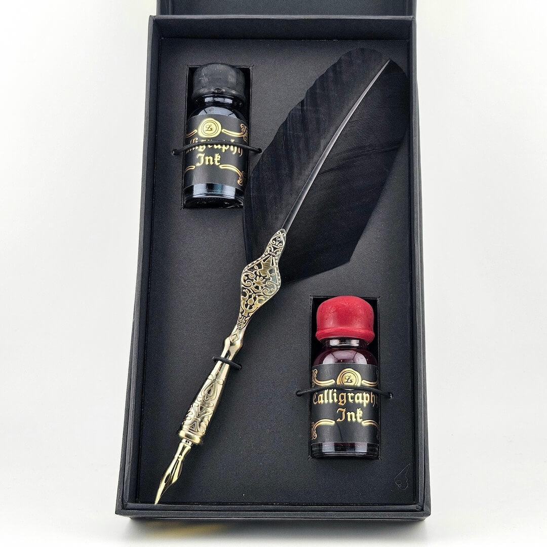 Feather pen set with ink bottles in a black box on a white background