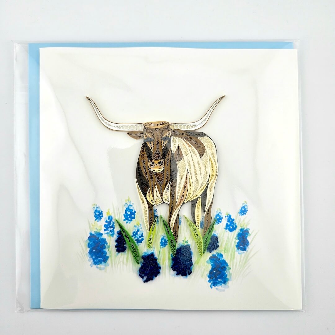 Greeting card with a longhorn cow and blue flowers on a white background