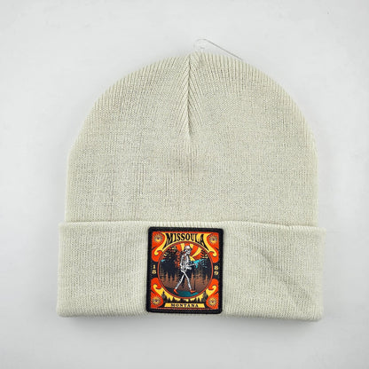 Beige knit beanie with a colorful patch featuring a skeleton and text on a white background
