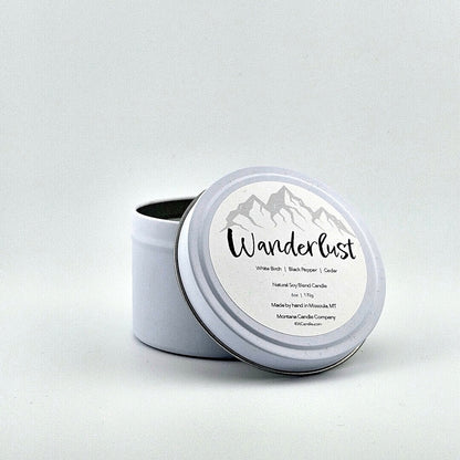 Metal tin candle label with label with gray mountain silhouette above printed script name above scent components.