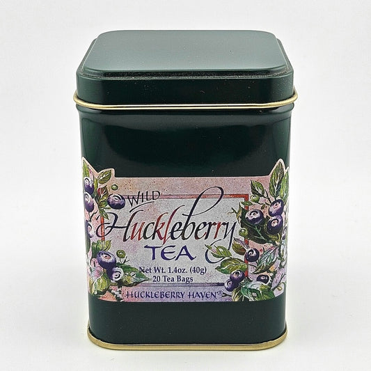 Dark green metal tin with label featuring painting of huckleberries framing product information.