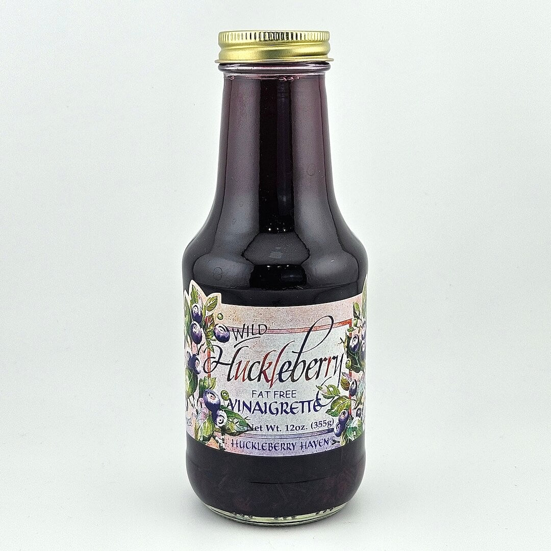 Glass bottle with gold lid. Label has painting style huckleberries framing product information print.