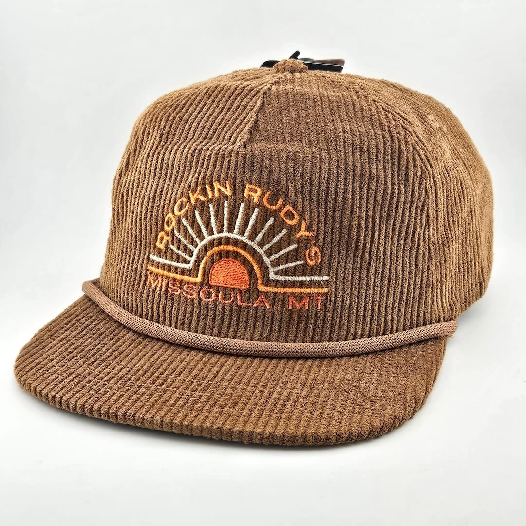 Brown corduroy billed hat with "ROCKIN RUDY'S", radiating from sunburst, "MISSOULA, MONTANA" along horizon bottom.