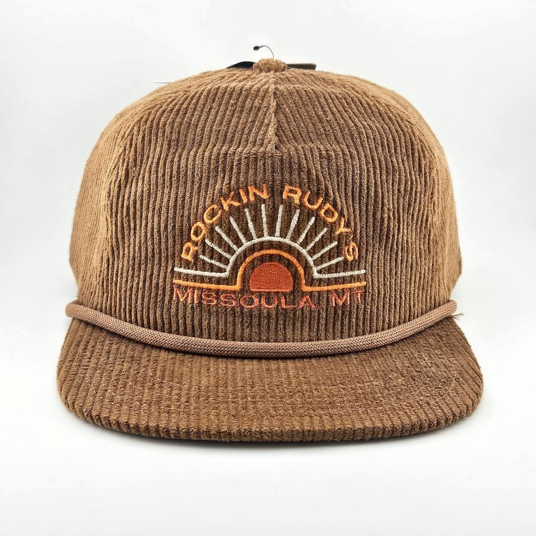 Brown corduroy billed hat with "ROCKIN RUDY'S", radiating from sunburst, "MISSOULA, MONTANA" along horizon bottom.