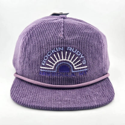 Purple corduroy billed hat with "ROCKIN RUDY'S", radiating from sunburst, "MISSOULA, MONTANA" along horizon bottom.