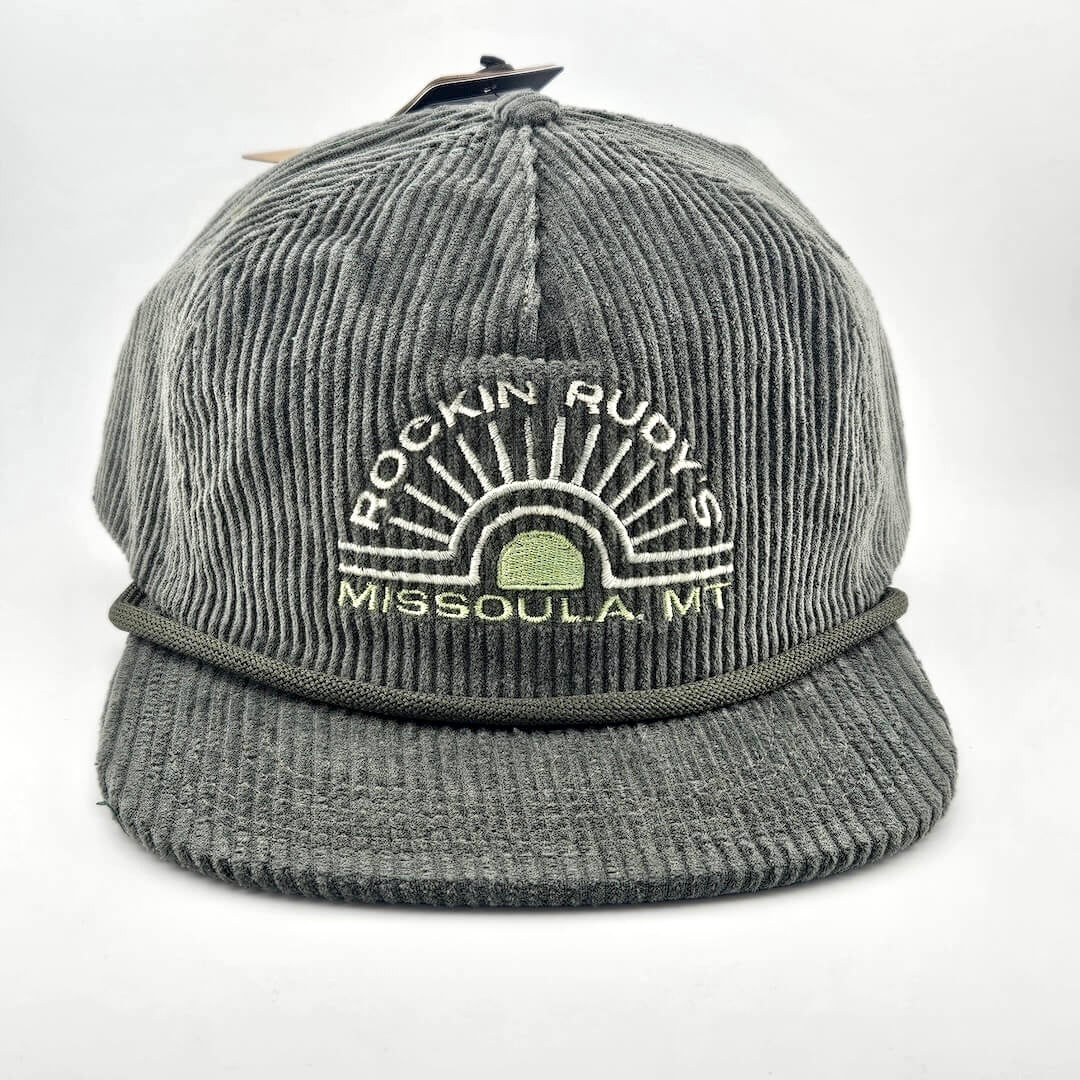 Green corduroy billed hat with "ROCKIN RUDY'S", radiating from sunburst, "MISSOULA, MONTANA" along horizon bottom.