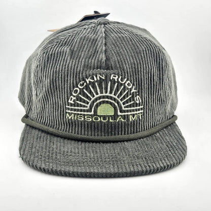Green corduroy billed hat with "ROCKIN RUDY'S", radiating from sunburst, "MISSOULA, MONTANA" along horizon bottom.