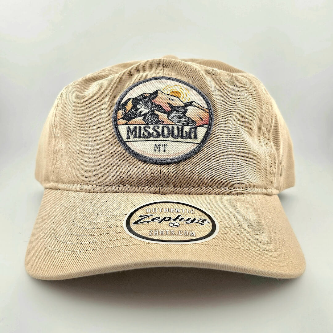 Beige cap with 'Missoula MT' and 'Zephyr' logos on a light gray background