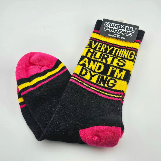 Black socks with hot pink toes and heels, pink and yellow stripes, and text, "Everything hurts and I'm dying."