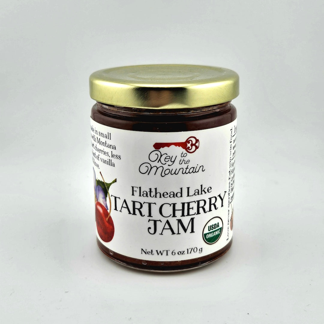 Jar of Flathead Lake Tart Cherry Jam with a gold lid on a white background