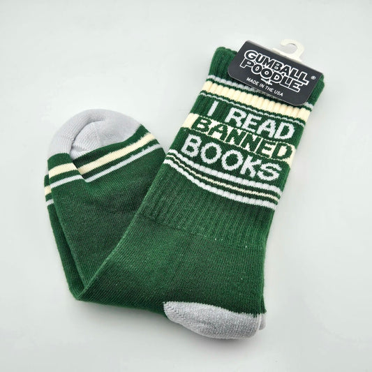 Green socks with light gray toes and heels, cream and gray stripes with text, "I read banned books."